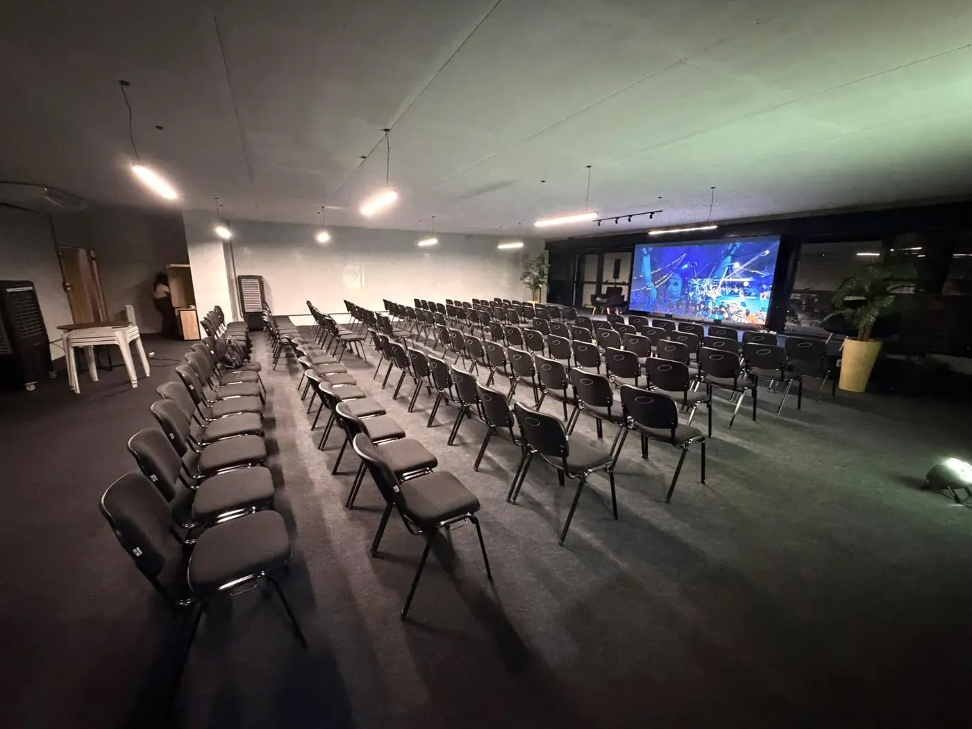 Auditório do SPACE B montado para o evento, com cadeiras enfileiradas e telão